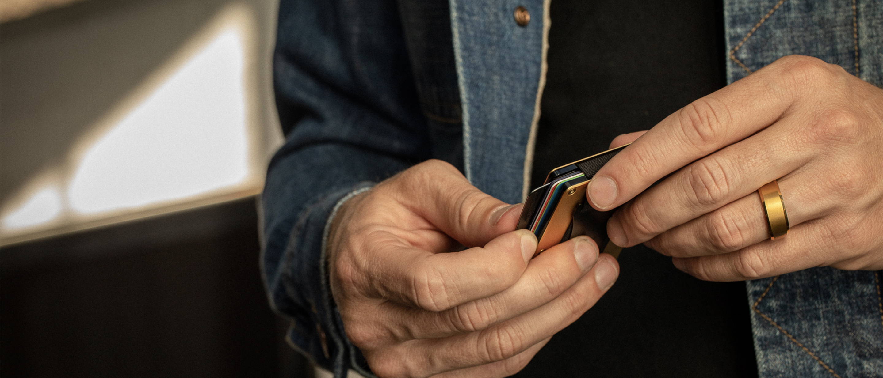 uomo che controlla le carte mentre indossa un anello smussato da 8 mm in oro 24 carati Ridge al dito