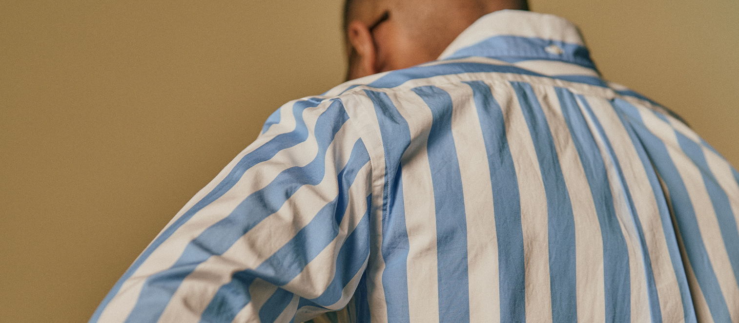 Person wearing a striped shirt, looking down against a plain background.