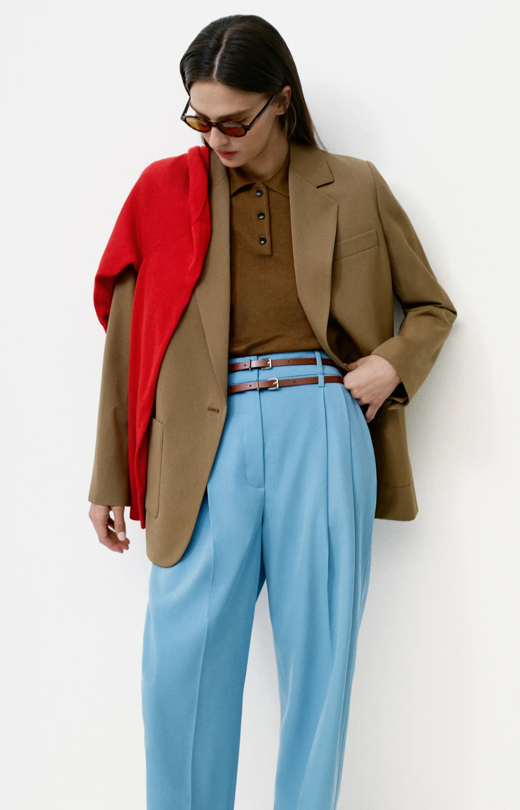 Person wearing a brown blazer, brown polo, blue trousers, and red sweater.