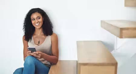 Photo of woman sitting inside looking at her mobile phone
