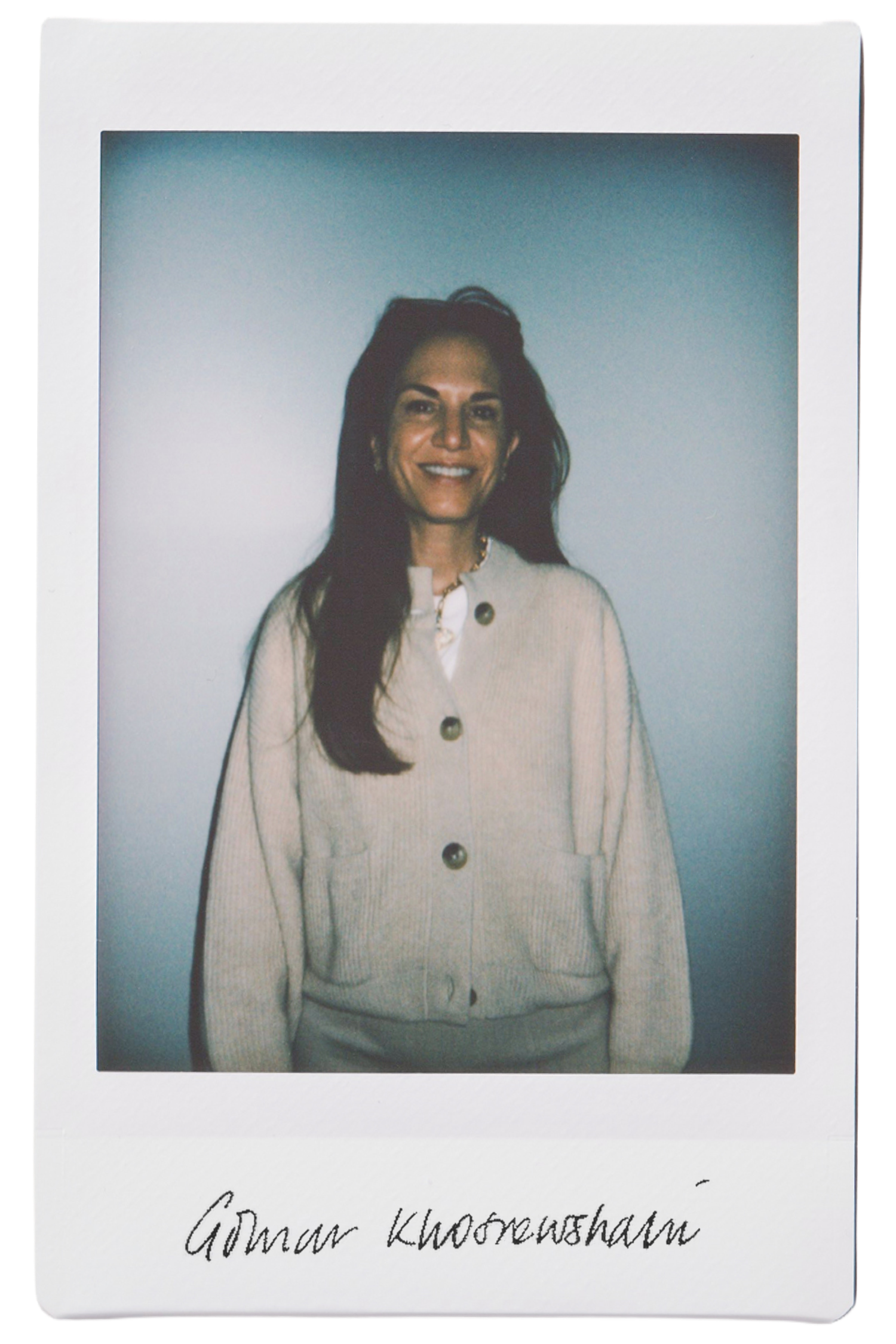 Woman smiling in a cozy sweater, with a soft blue background.
