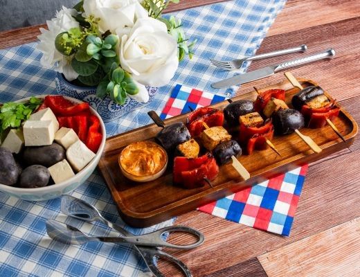 Skewers with vegetables and dip, alongside a bowl of tofu and peppers.