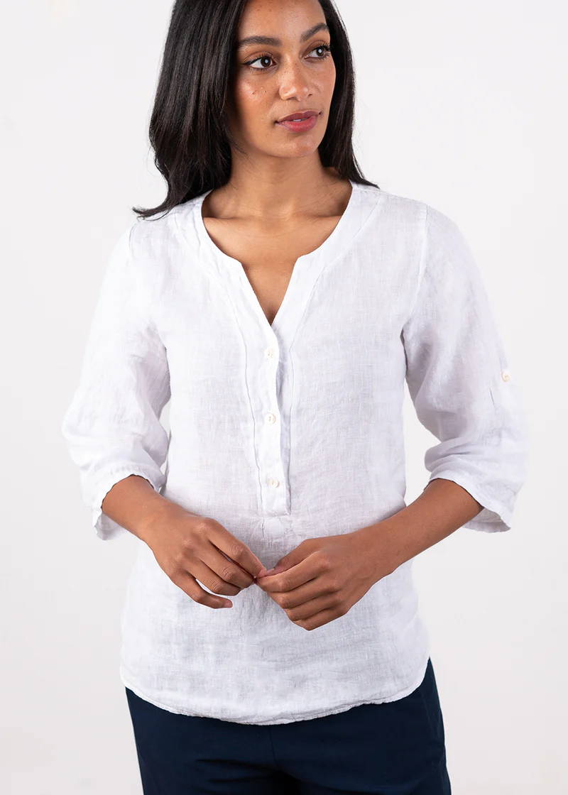 A model wearing a white 3/4 sleeve linen blouse with button down detailing and black trousers