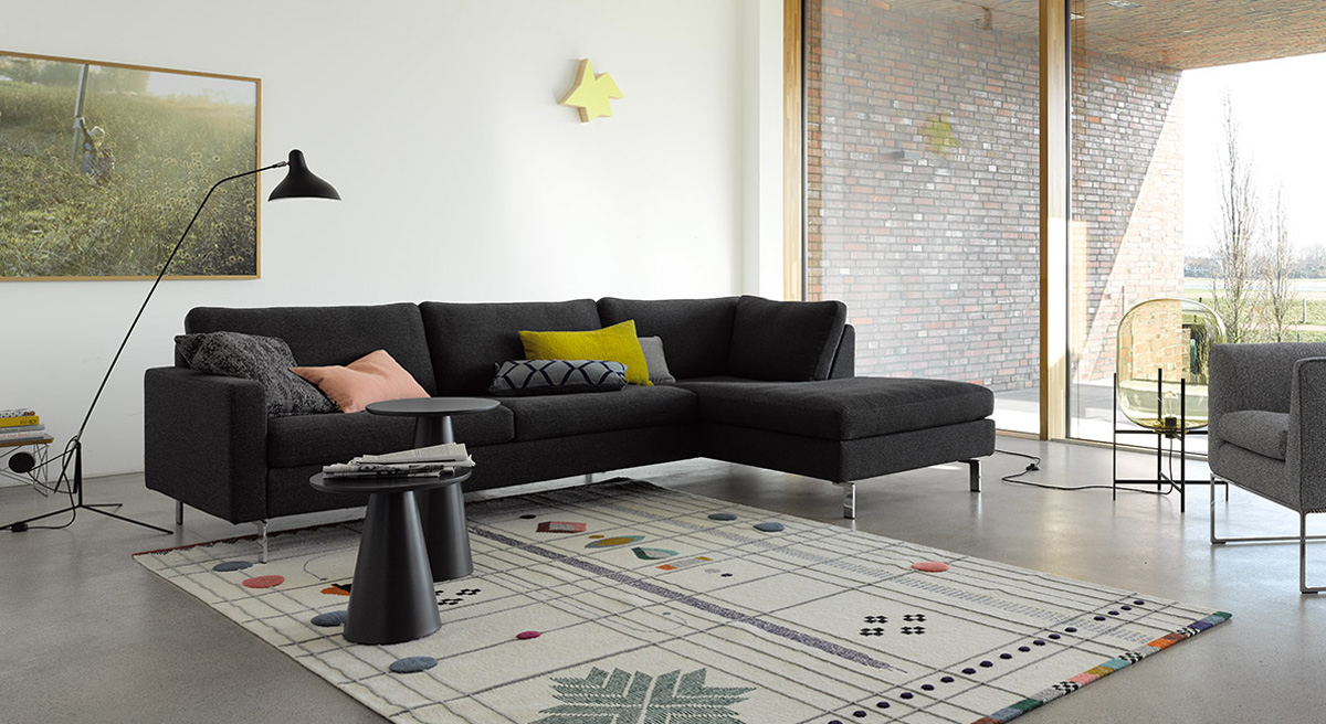 Modern living room with black COR Conseta sofa and patterned rug.