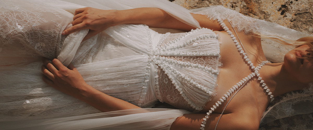 Bride in a delicate white dress with intricate details and a flowing veil.