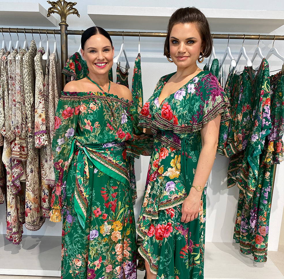 Two CAMILLA Styling Angels wearing Long Rich Green Dresses with colourful Florals