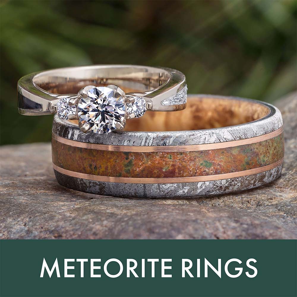 Two meteorite rings, one with a diamond, displayed on a textured surface.