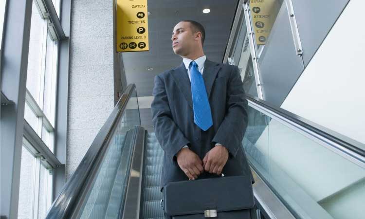 Man wearing suit and blue tie on escalator