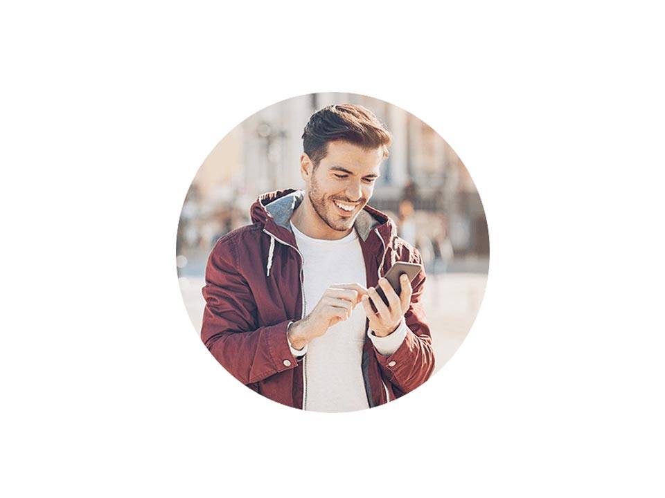 A Caucasian man wearing a hoodie smiles while he checks his phone