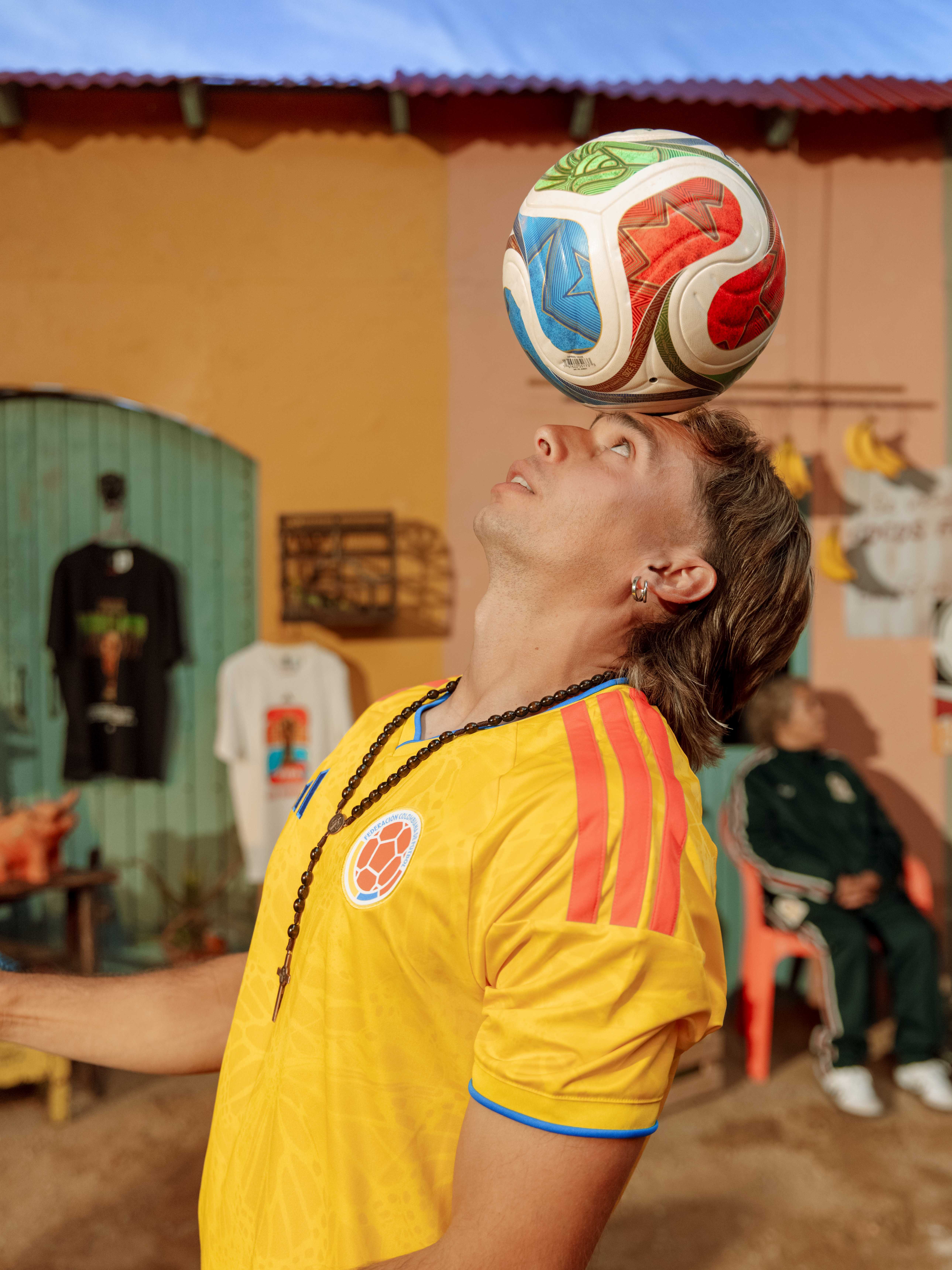 Person balancing a soccer ball on their forehead, wearing a yellow jersey.