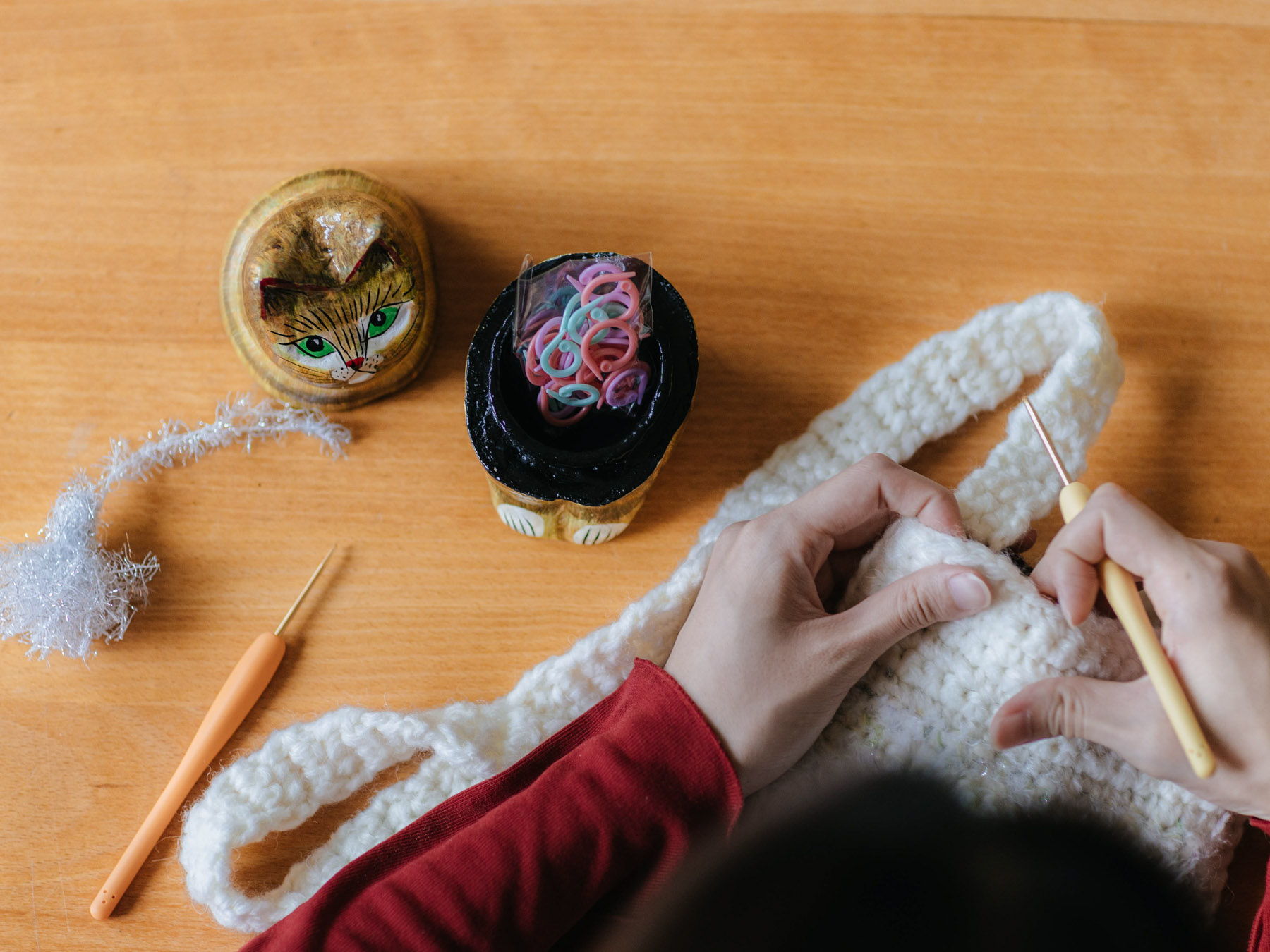 Person crocheting with yarn and tools on a wooden table.