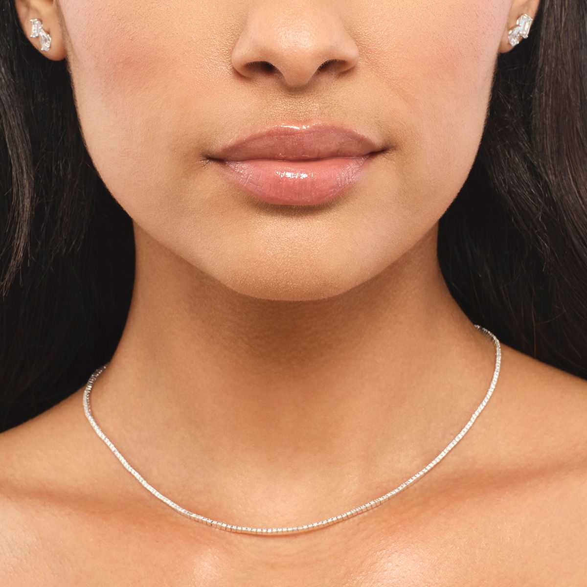 Close-up of a woman's neck wearing a simple silver necklace.