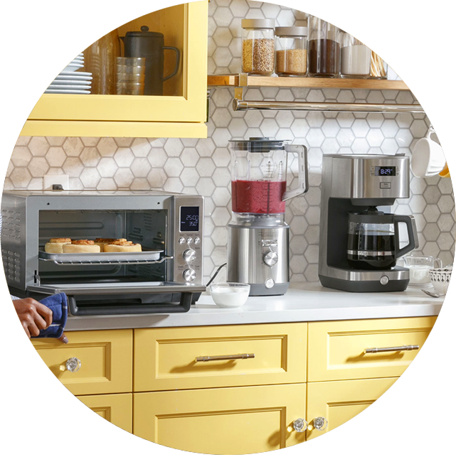 Kitchen countertop with toaster oven, blender, and coffee maker against yellow cabinets.