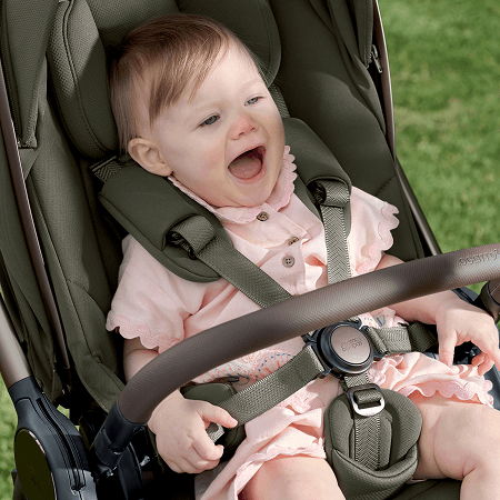Baby smiling in a stroller, wearing a pink outfit.