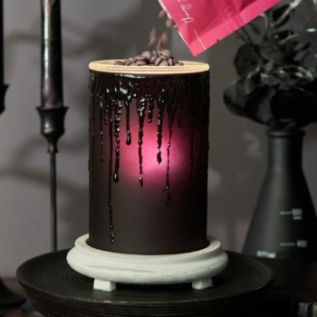 Candle melting with colored wax dripping, illuminated from within.