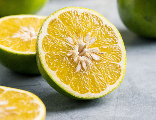 A sliced yellow lime with seeds on a gray surface.
