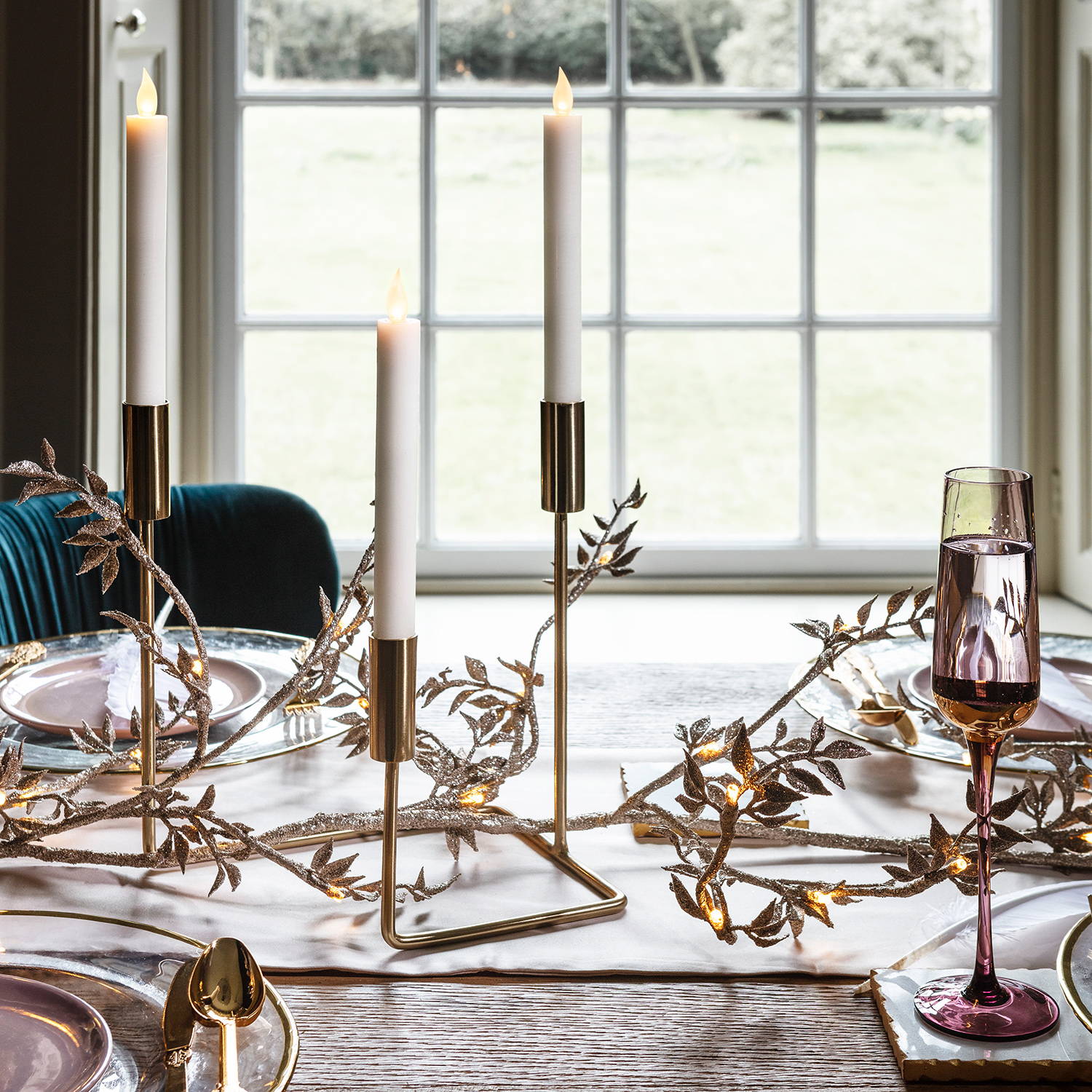 gold candelabra on top of a Christmas table with a matching gold garland
