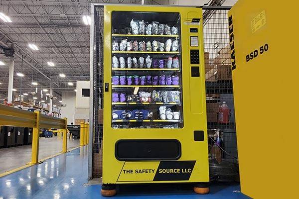 PPE Vending Machine in large manufacturing facility, with yellow guardrails protecting machine from oncoming forklift traffic.