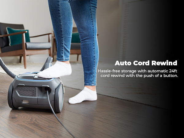 Person using a vacuum cleaner with auto cord rewind feature.