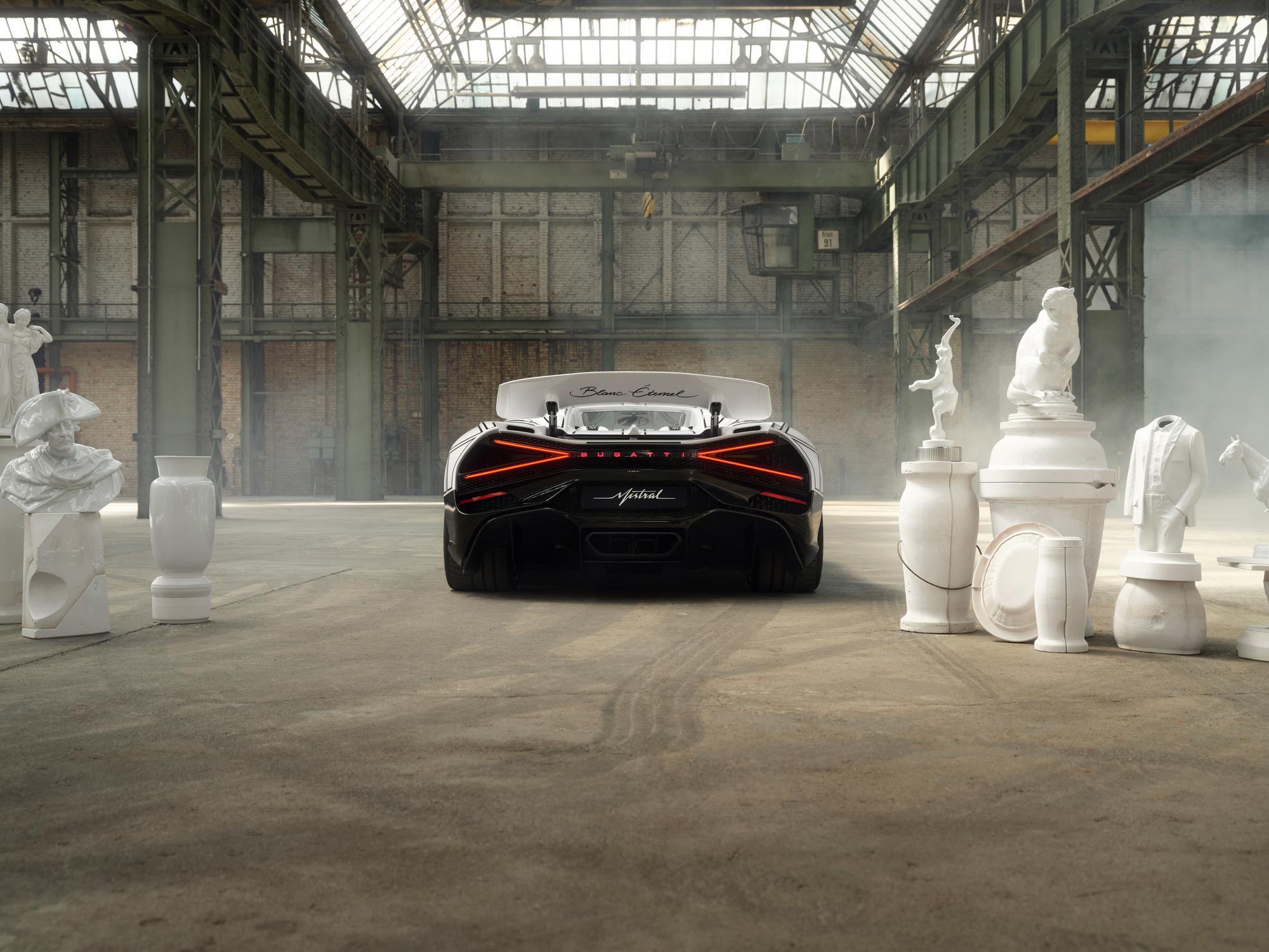 A sleek car surrounded by white sculptures in an industrial setting.