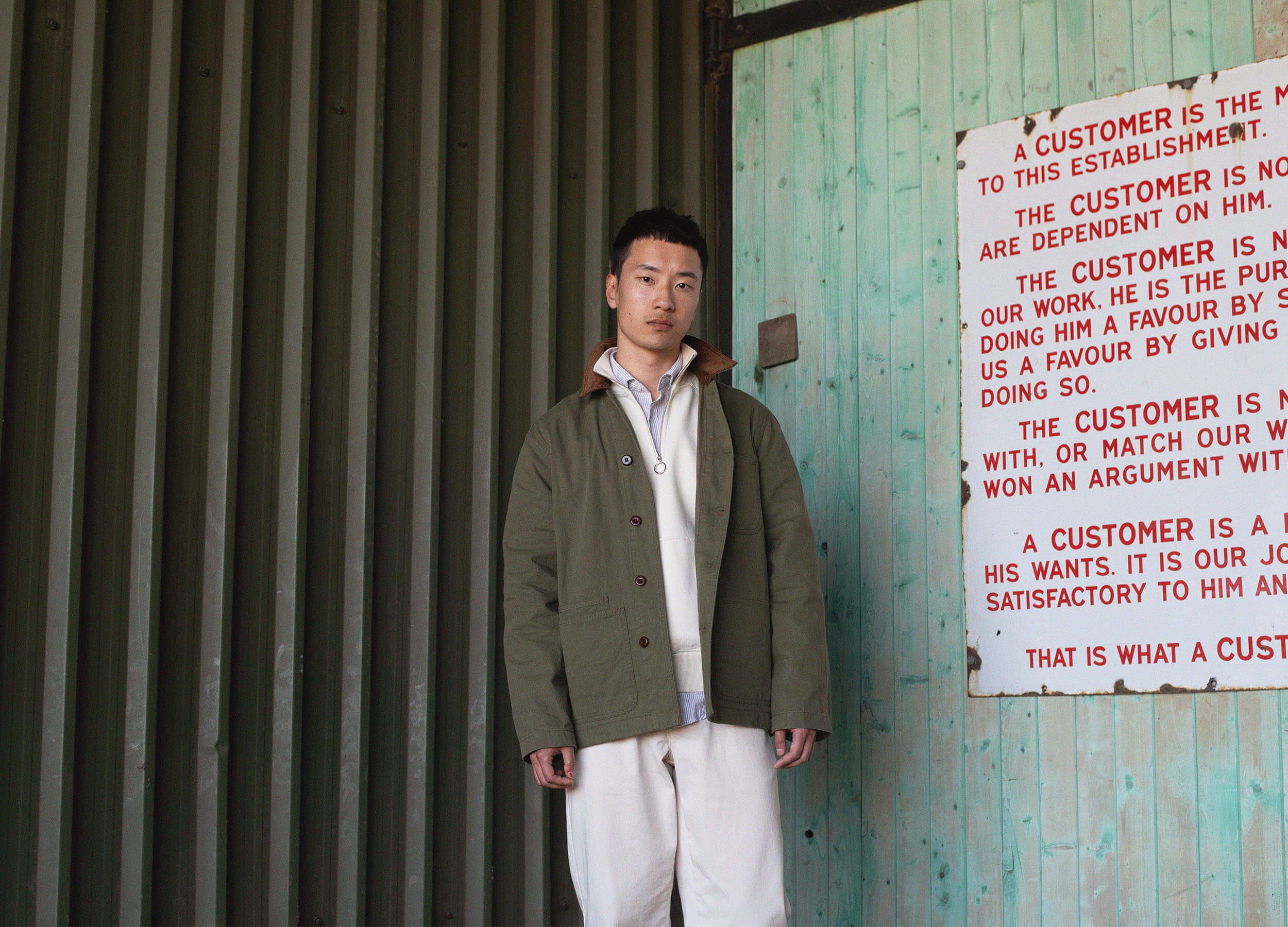 A person standing next to a wall with text and colorful background.