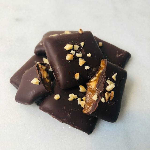 Hazelnut toffee squares piled on marble countertop