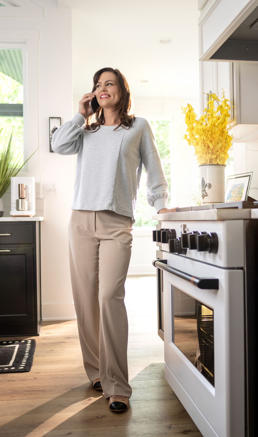 Woman talking on the phone in a modern kitchen.