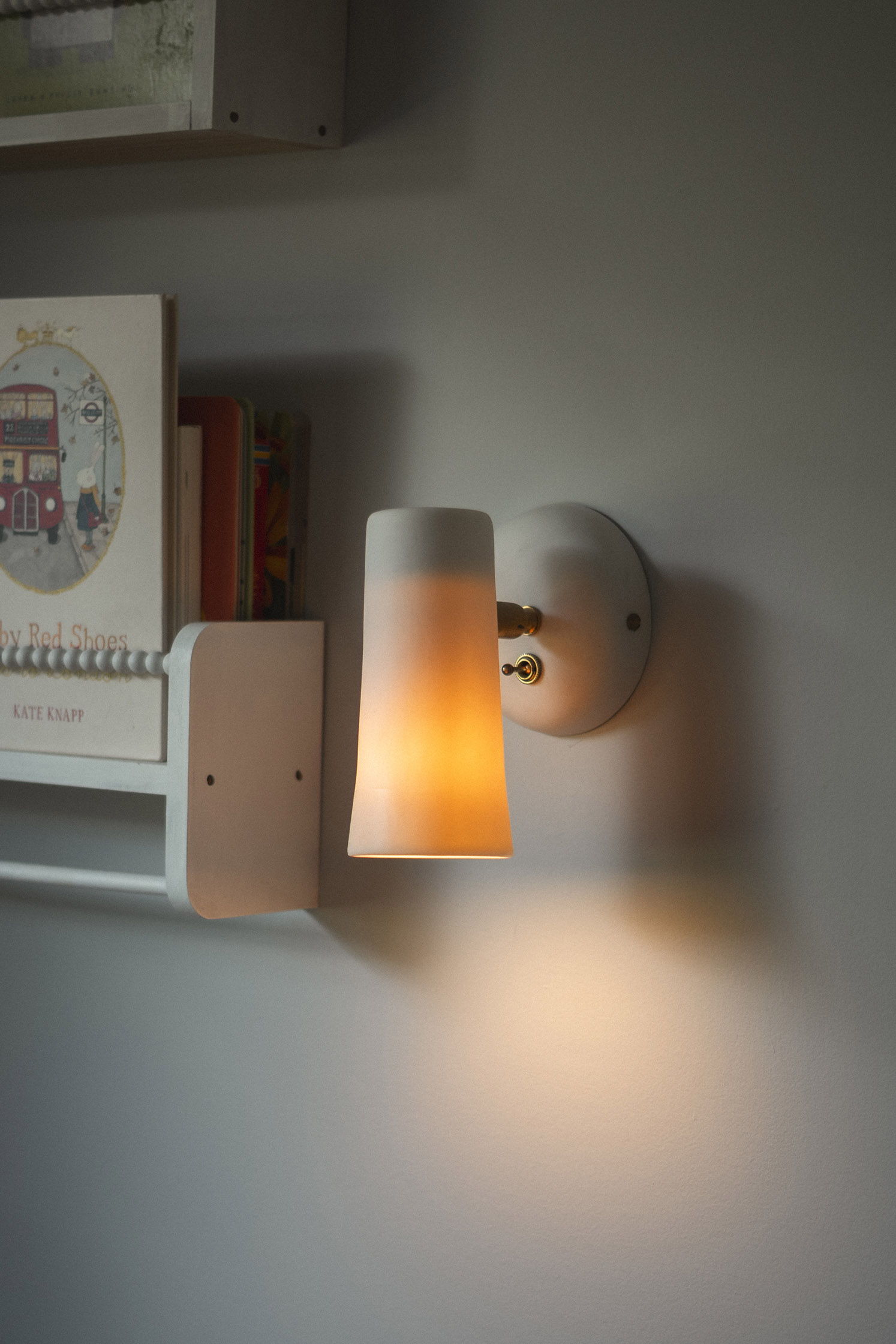 A wall-mounted lamp casting warm light in a softly lit room.