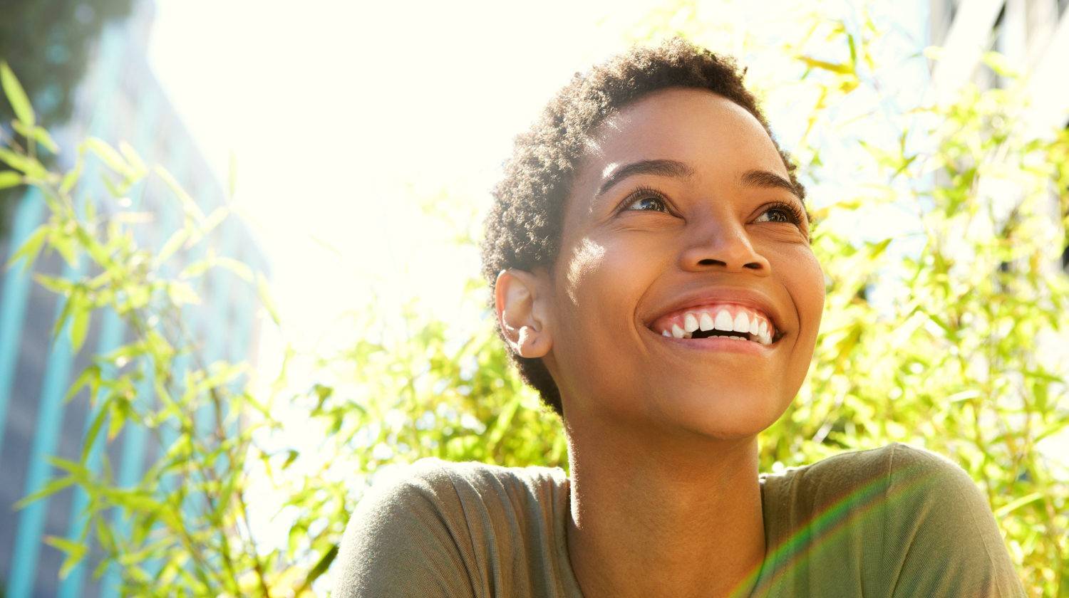 Close up portrait of beautiful young black woman smiling outdoors | What Is Epigenetics: Your Mind’s Influence Over Your Health | Featured