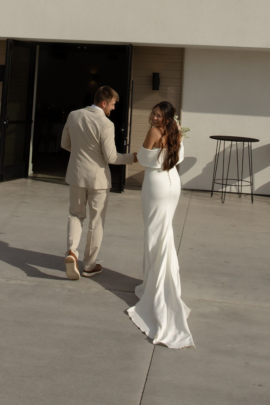 A couple walking together, the woman in a white wedding dress.