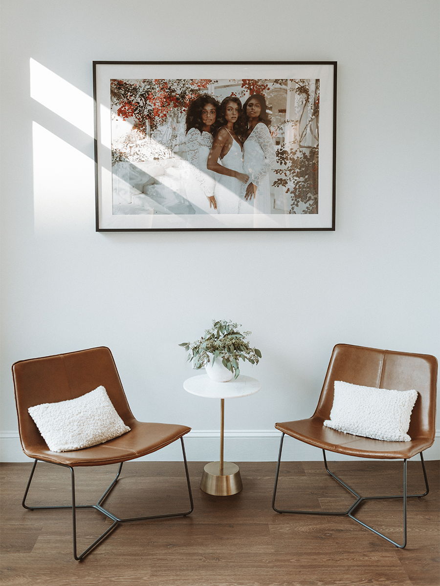 Two modern chairs with pillows, a table, and a framed photo on the wall.