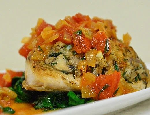 Grilled fish topped with tomato salsa on a bed of spinach.
