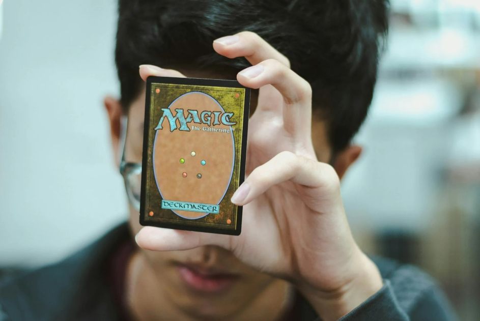 Person holding a card in front of their face, blurred background.