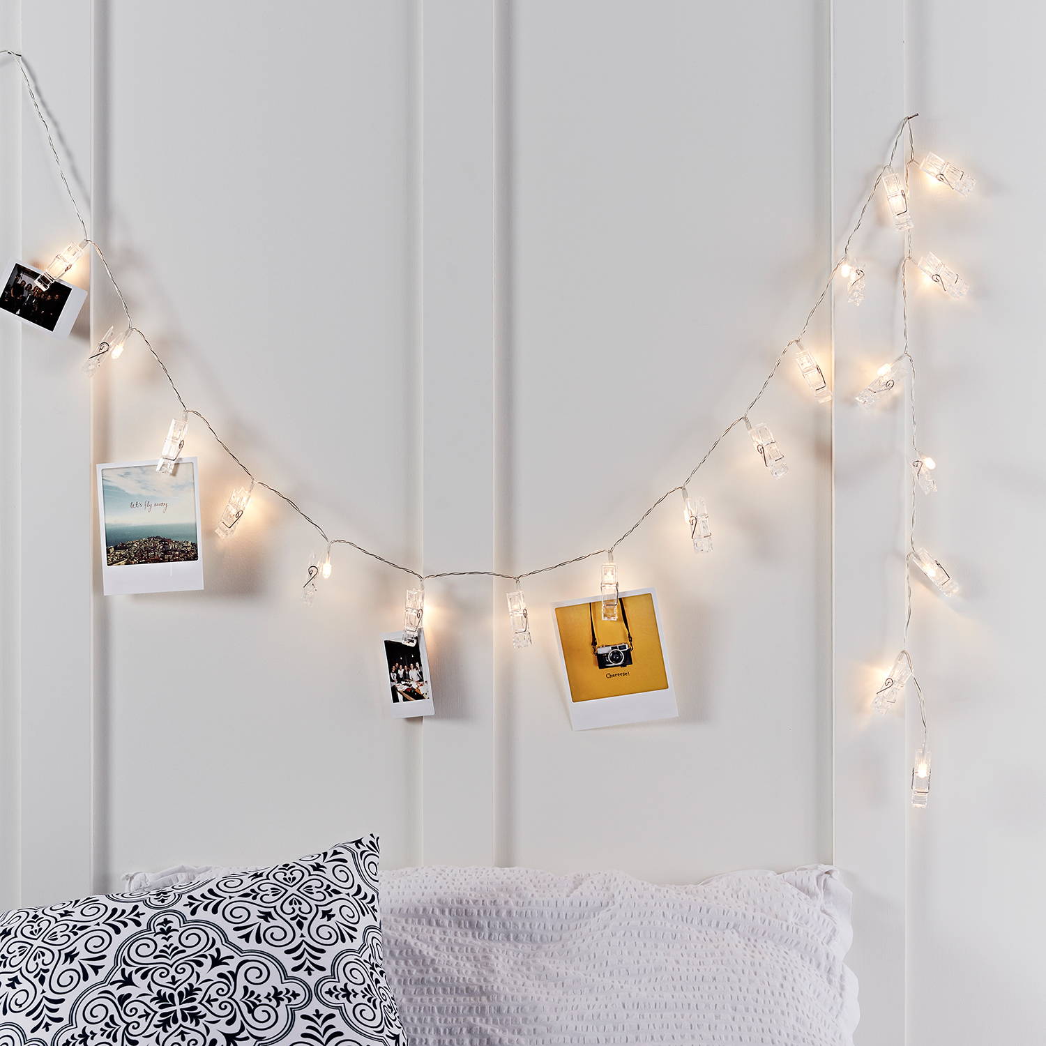 Peg string lights with photos above the bed