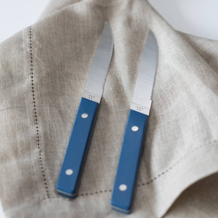 Two Blue Misen Steak Knives seen from above, resting atop a beige linen cloth.