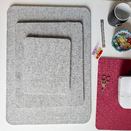 three sizes of wool pressing mats stacked next to a sewing machine and sewing tools