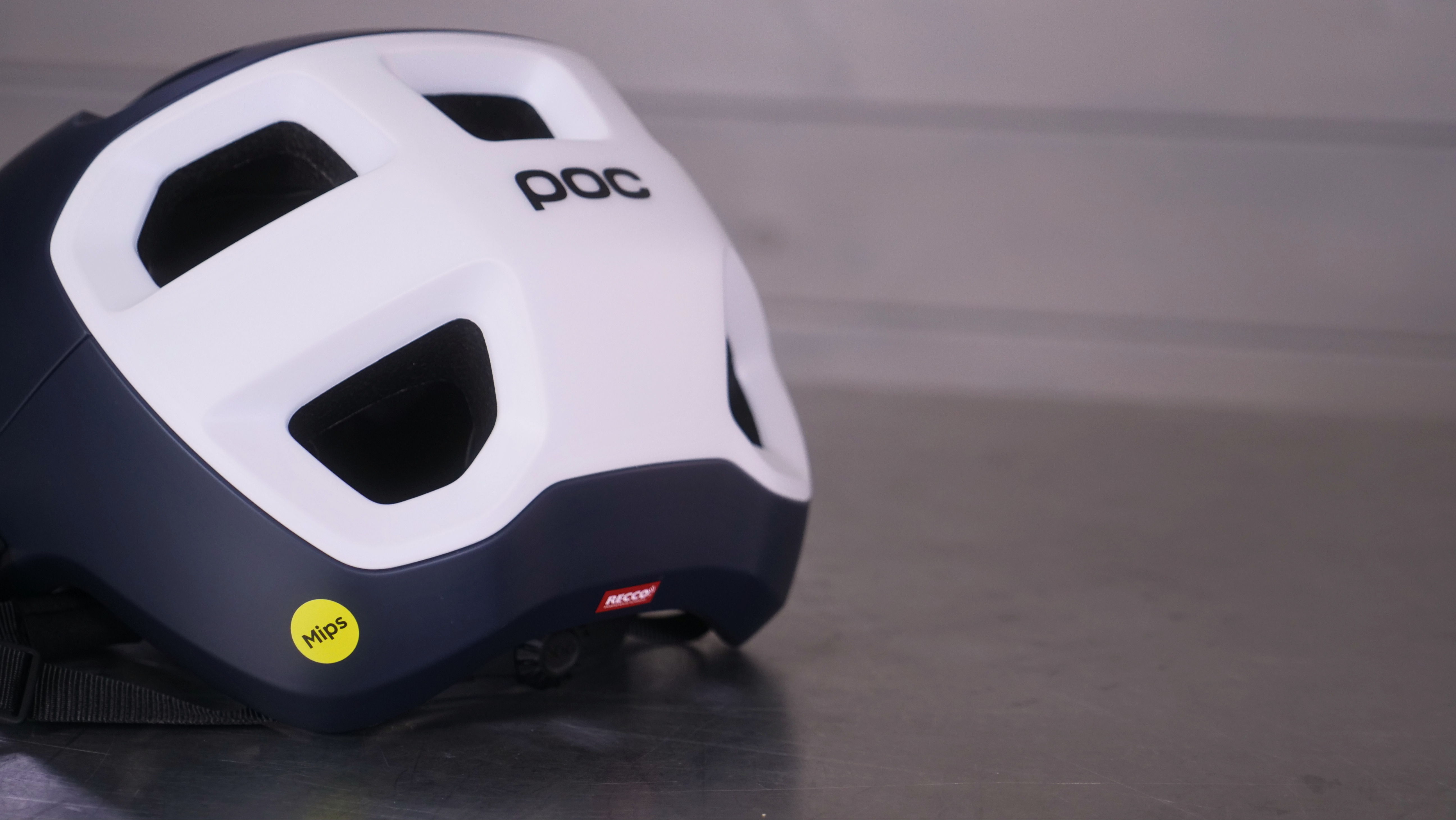 White and navy cycling helmet on a metallic surface.