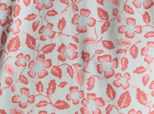Floral fabric pattern with pink flowers and green leaves on a light background.