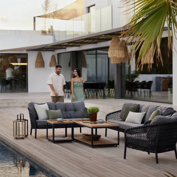 Ocean Large Outdoor 2-Seater Sofa with gray cushions and deep seating, positioned in a modern poolside setting with a luxurious wooden table centerpiece and scenic mountain views