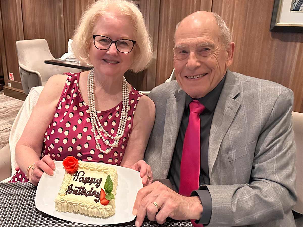 Retired couple dressed formally in dress and tie and birthday cake