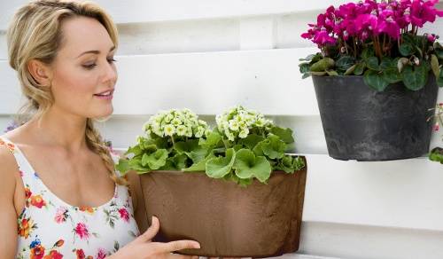 Woman inspecting the plants in wall planters hung on outside of a house