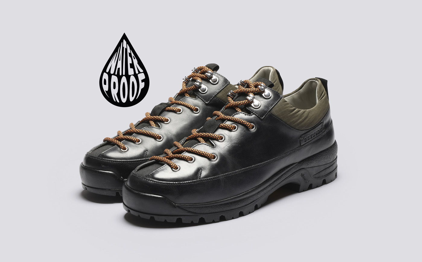 Grenson Sneaker 70. Black and gray waterproof shoes with brown laces on a gray background.