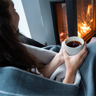 Woman holding cup of coffee while wrapped in Merino SoftWool Blanket