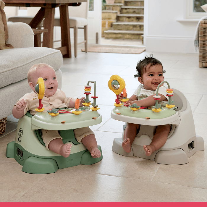 Two babies sitting in activity centers on a tiled floor.