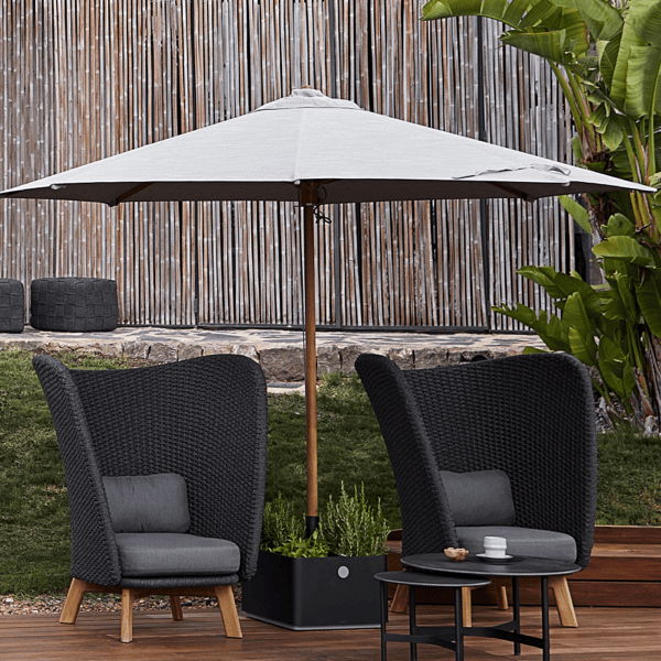 Weather-resistant woven outdoor lounge chairs and patio umbrella on a wood deck with built-in planters