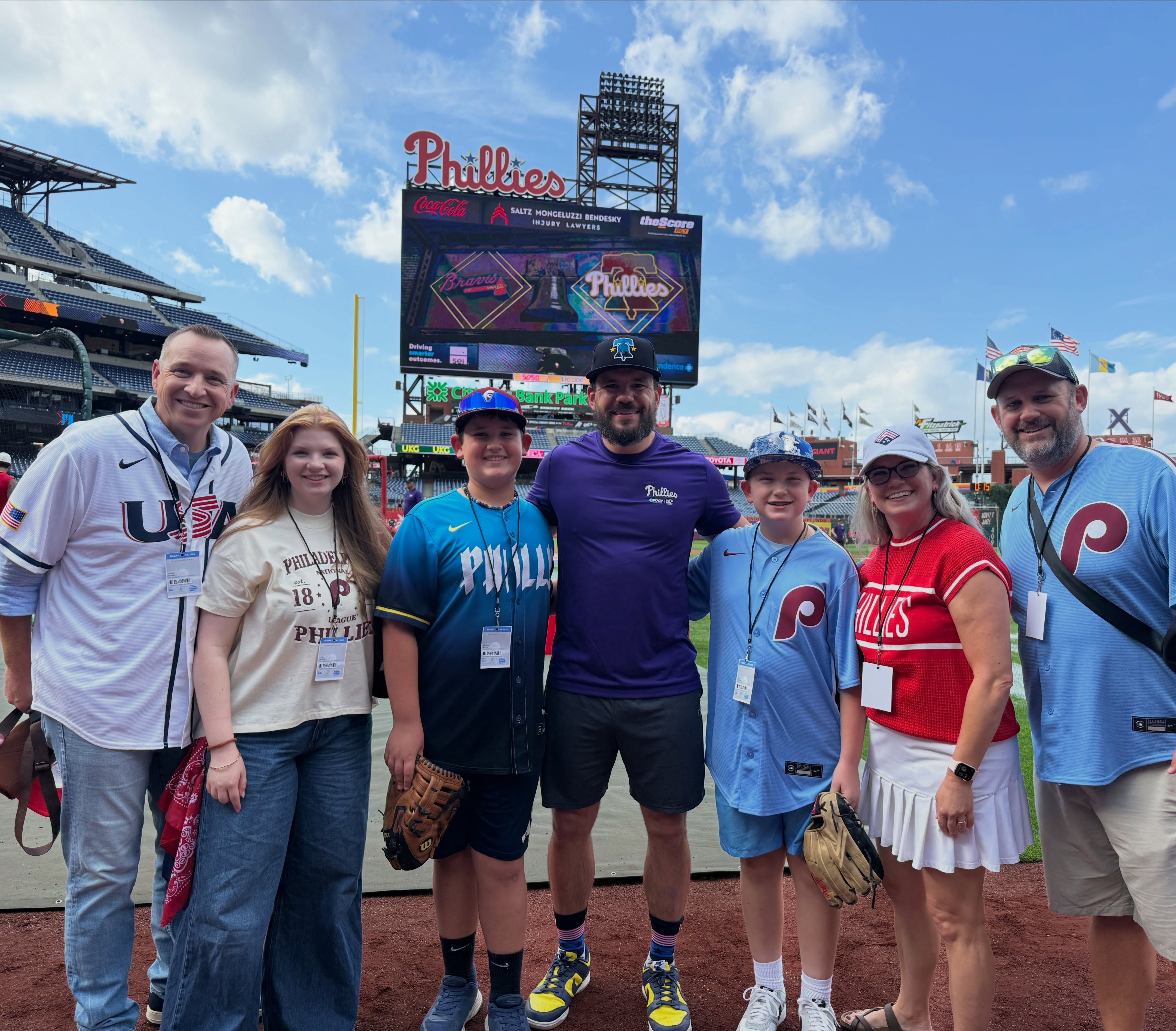Group of people at a baseball stadium, smiling and posing for a photo.