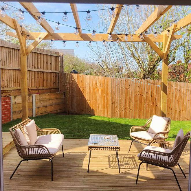 Festoons hung from pergola above outside decking area with seating