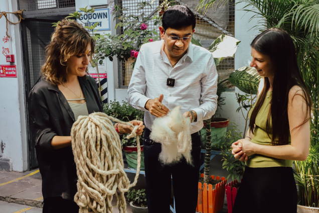 Drei Menschen besprechen Materialien mit Wolle in der Hand