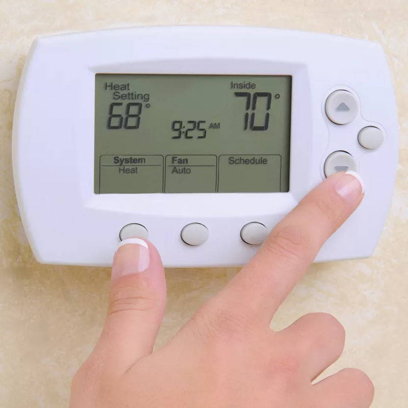 person adjusting heat pump thermostat