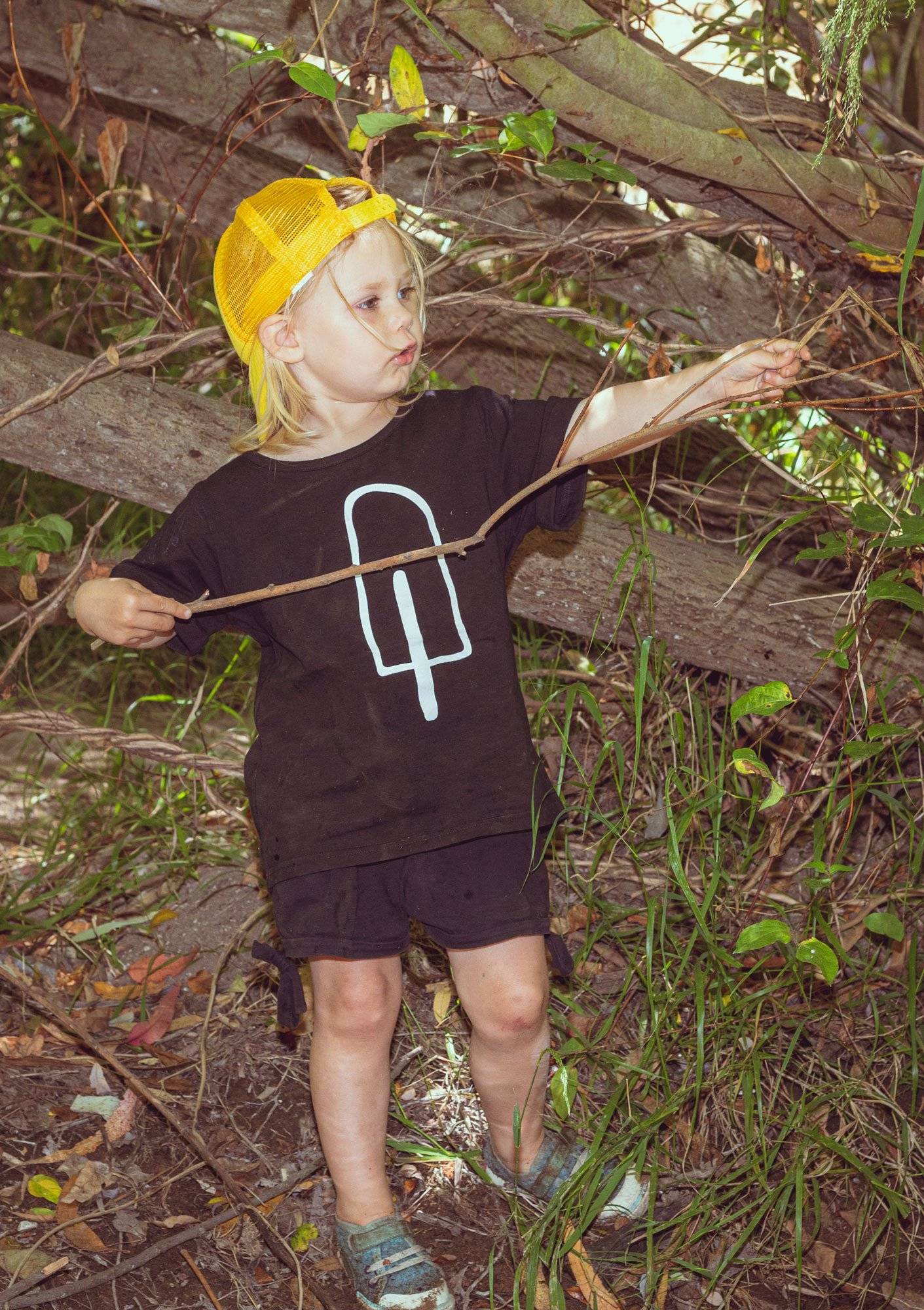 Young boy with a yellow cap and black shirt with popsicle design